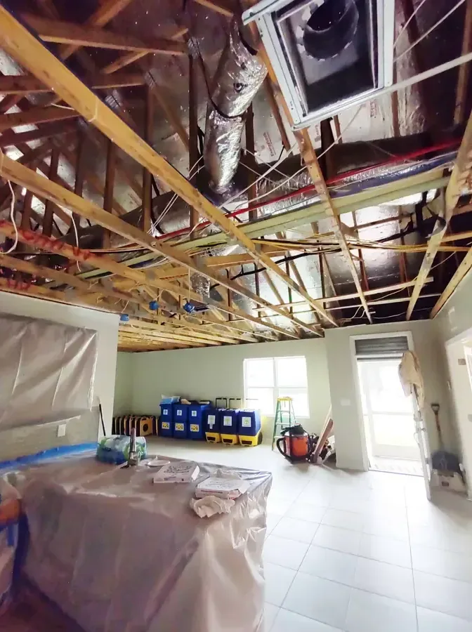 A ceiling opened under plastic containment with drying equipment running below